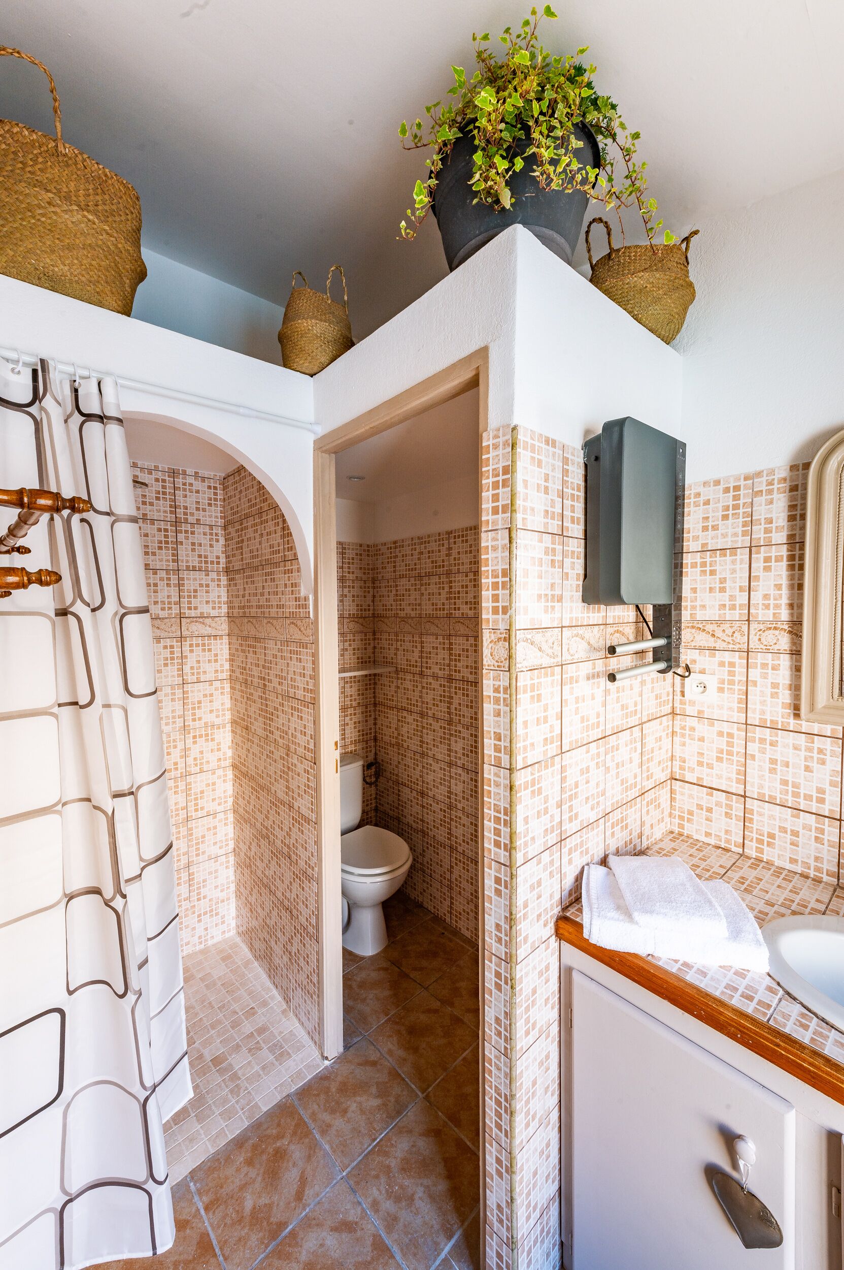 Ein Badezimmer mit Fliesenboden, Toilette, Waschbecken und Duschbereich.