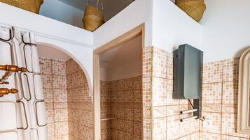 Ein Badezimmer mit Fliesenboden, Toilette, Waschbecken und Duschbereich.