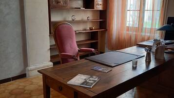 A room with a wooden desk, a chair, a bookshelf, and a window with curtains.