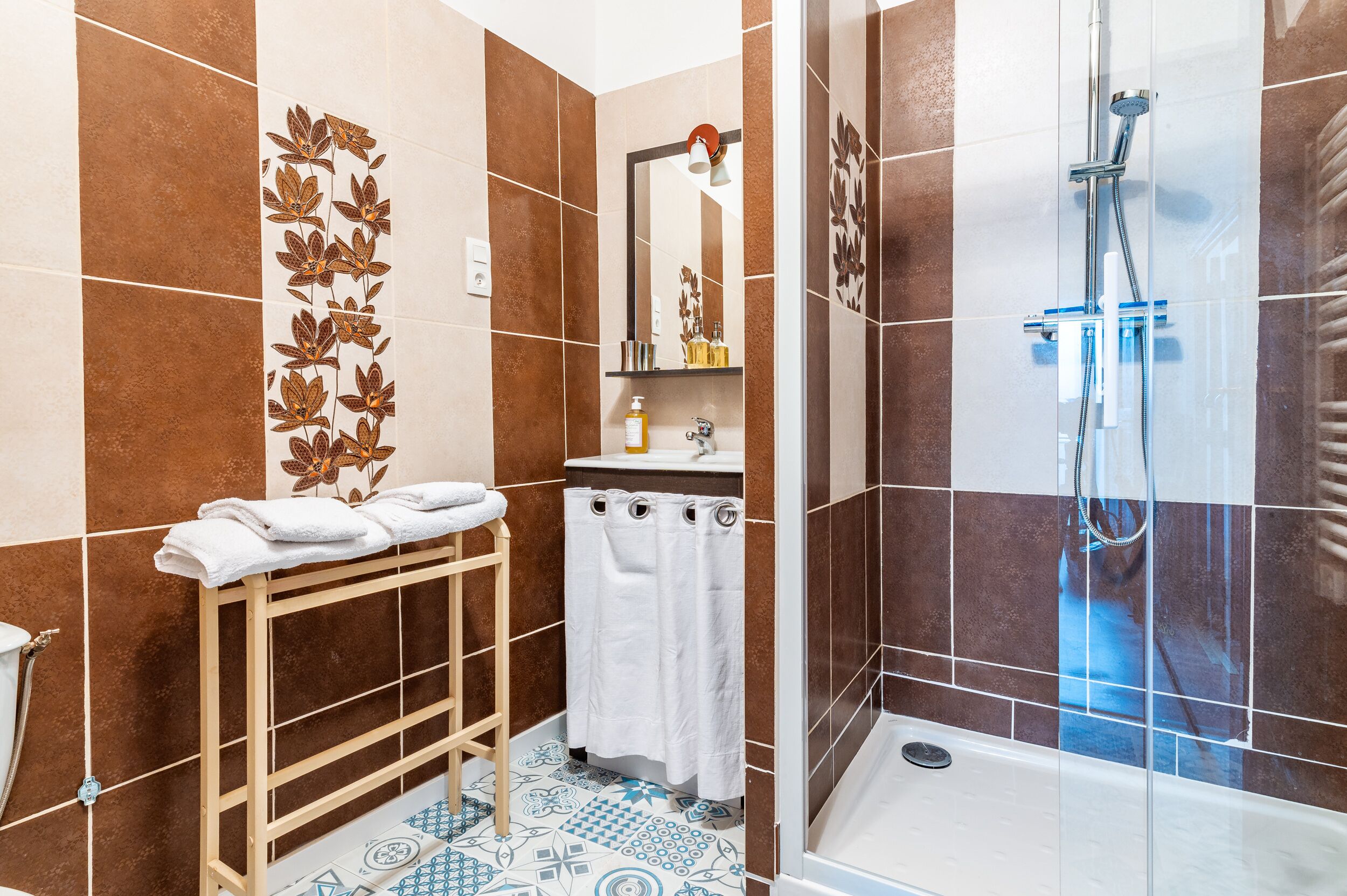 A bathroom with a shower, a sink, and a mirror.