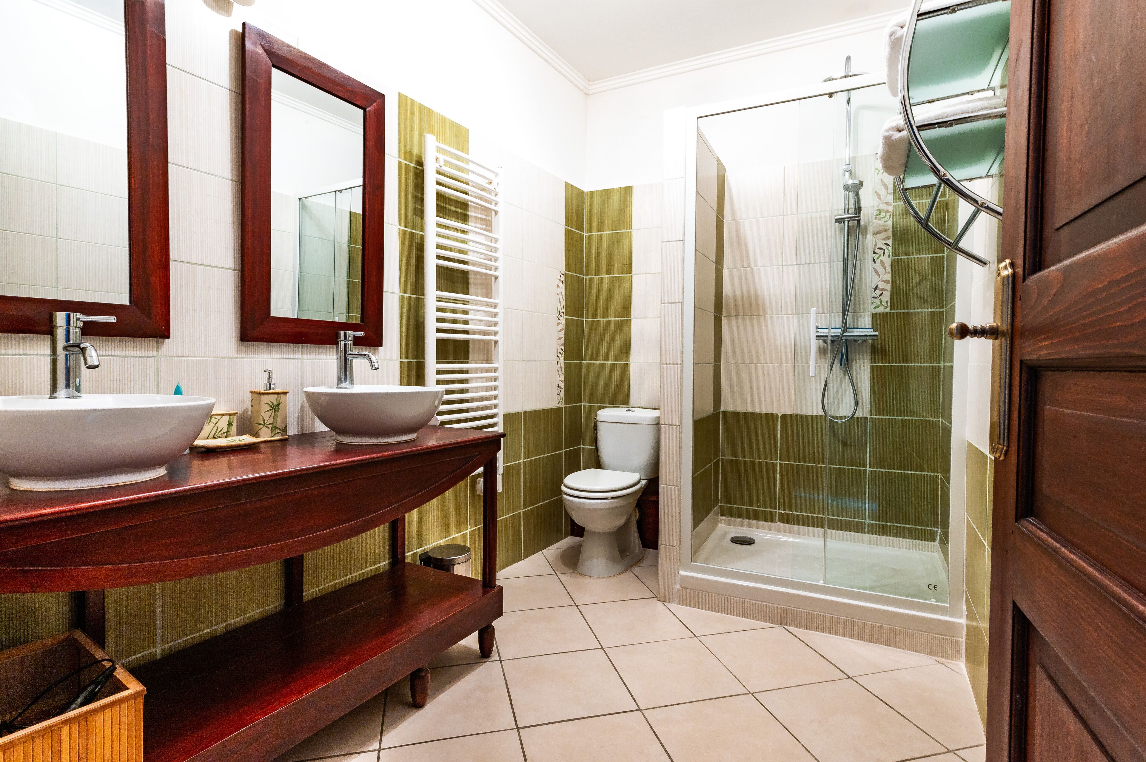 A bathroom with two sinks, a toilet, and a glass-enclosed shower.