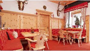 A traditional wooden interior with a red upholstered sofa, wooden benches, and a dining table with chairs. - Familienhotel Vent (Soelden)