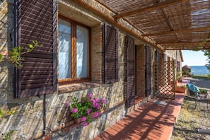 A stone building with shutters, a wooden porch, and a view of the sea. - Verdidea - Podere del Mezzadro (Radicofani)