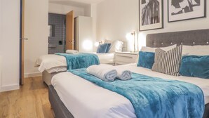 A hotel room with a large bed, a bedside table, a wardrobe, and a bathroom visible through an open door. - Tudors eSuites Birmingham Canalside Apartments (Birmingham)