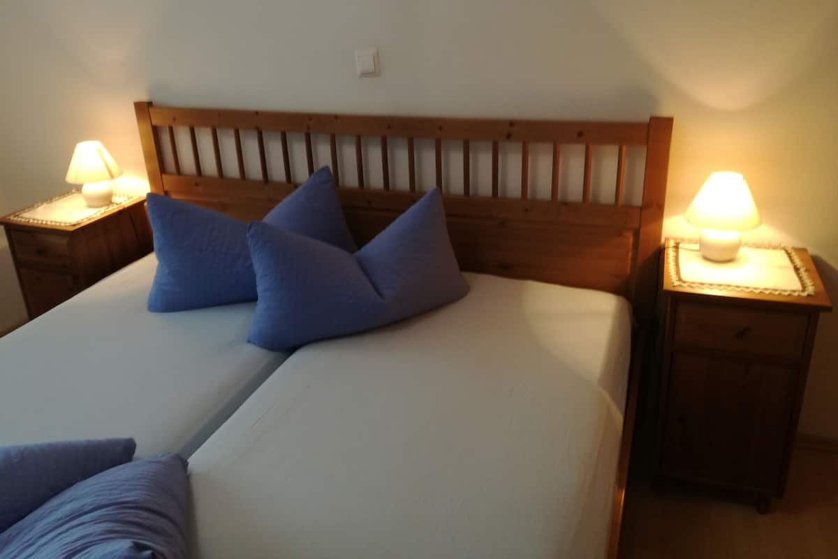 Una cama con cabecera de madera, dos mesitas de noche con lámparas y almohadas azules.