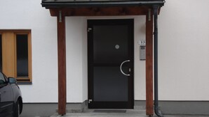A building entrance with a black door, a small overhang, and a sign indicating the address.