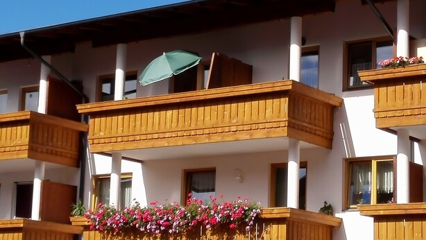 A multi-story building with balconies, wooden railings, and flower boxes.