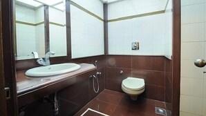Une salle de bain avec un lavabo blanc, des toilettes et un miroir.