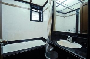 Un baño con bañera, lavamanos y espejo.