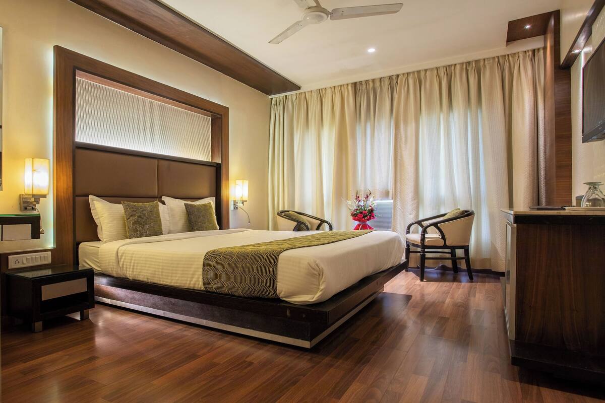Una habitación de hotel moderna con una cama grande, un escritorio, una silla y un ventilador de techo.