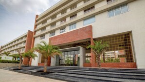 Un hôtel à plusieurs étages au design moderne, doté d’une entrée imposante avec des portes en verre et d’une façade en briques.