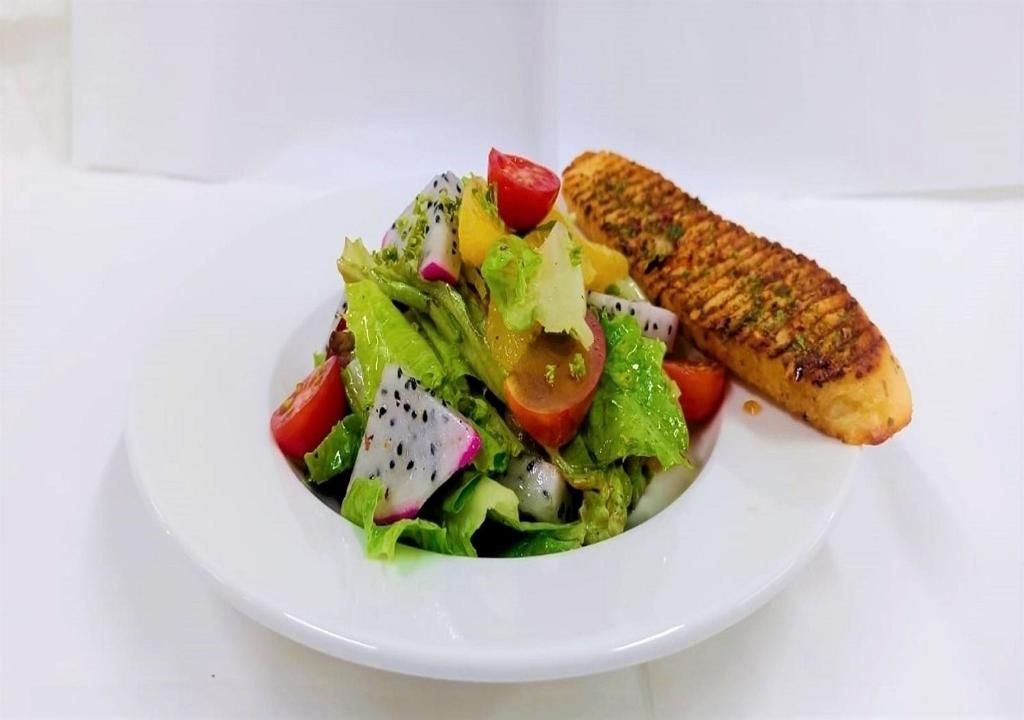 Een witte schaal met een salade en een gegrild gerecht.