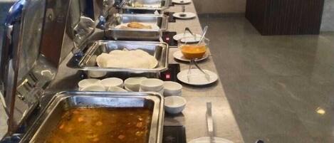Un buffet proposant une variété de plats, notamment un grand récipient de soupe, des salades et d’autres mets.