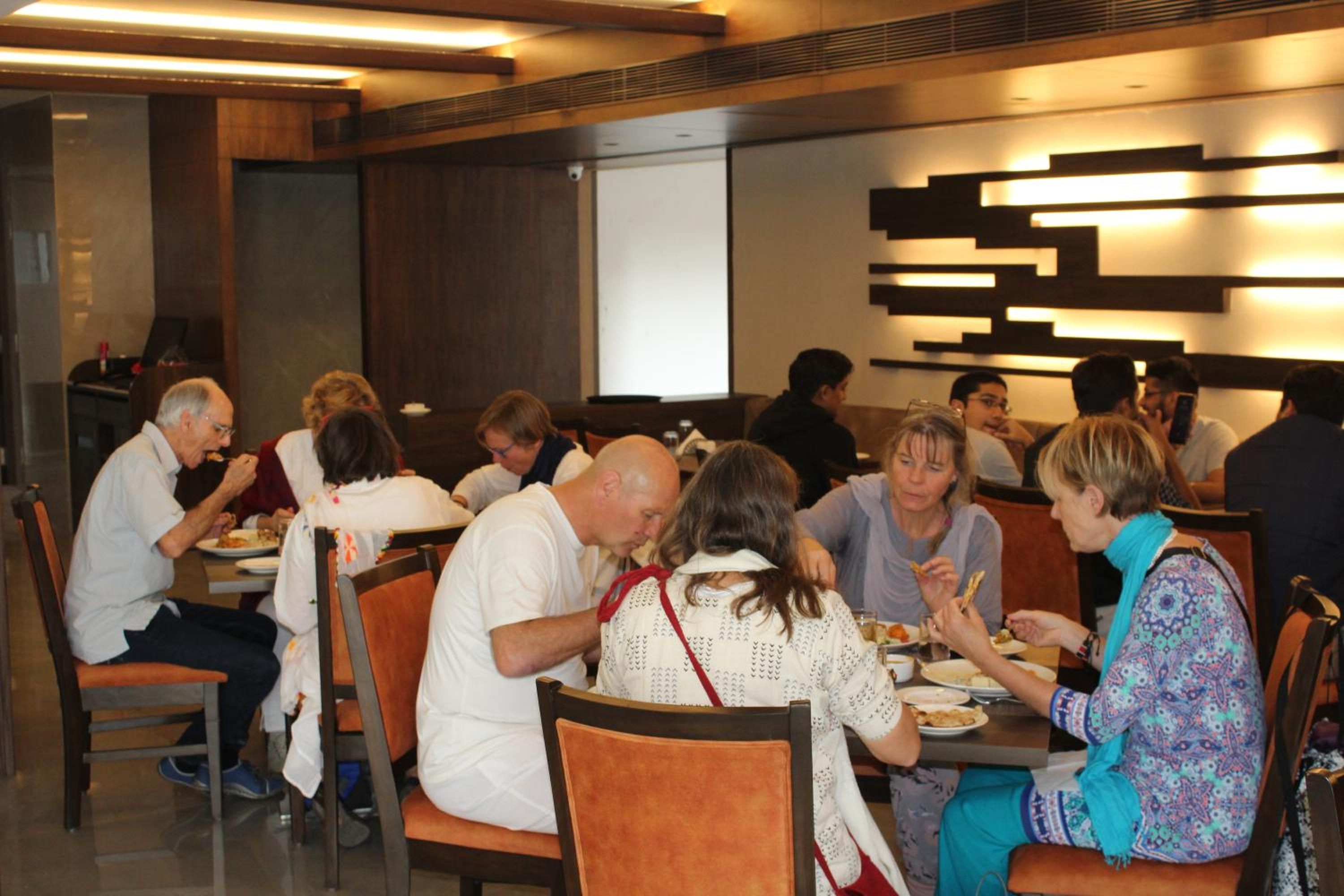 A dining area with multiple tables and chairs, a whiteboard on the wall, and a projector screen.
