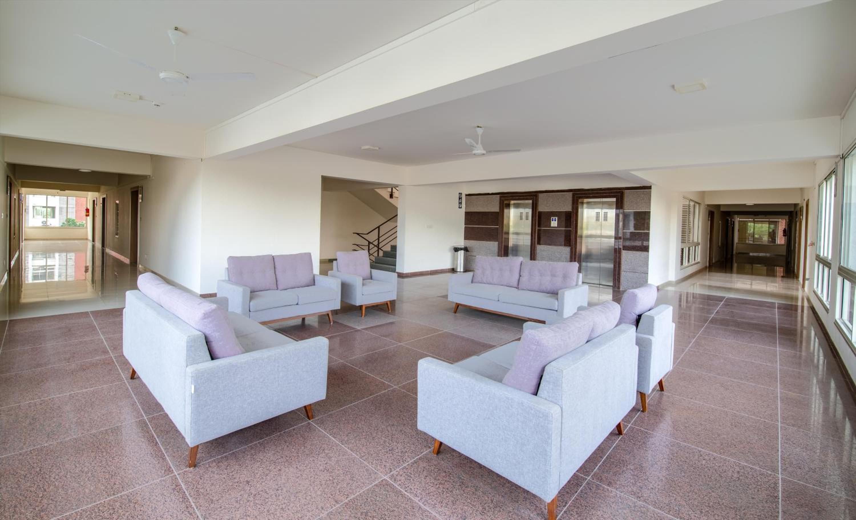 A spacious lobby with a high ceiling, a staircase, and a reception area.