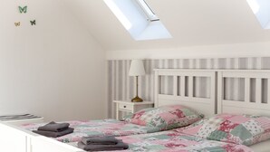 A bedroom with a skylight, striped wallpaper, a bed with floral bedding, and a bedside lamp. - Landhof Potsdam (Potsdam)