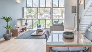 A modern living room with a glass coffee table, a sofa, and a dining area.