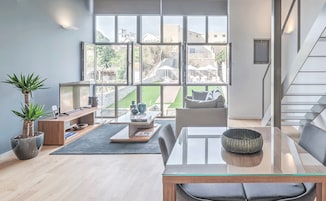Una sala de estar moderna con una mesa de centro de vidrio, un sofá y una zona de comedor.