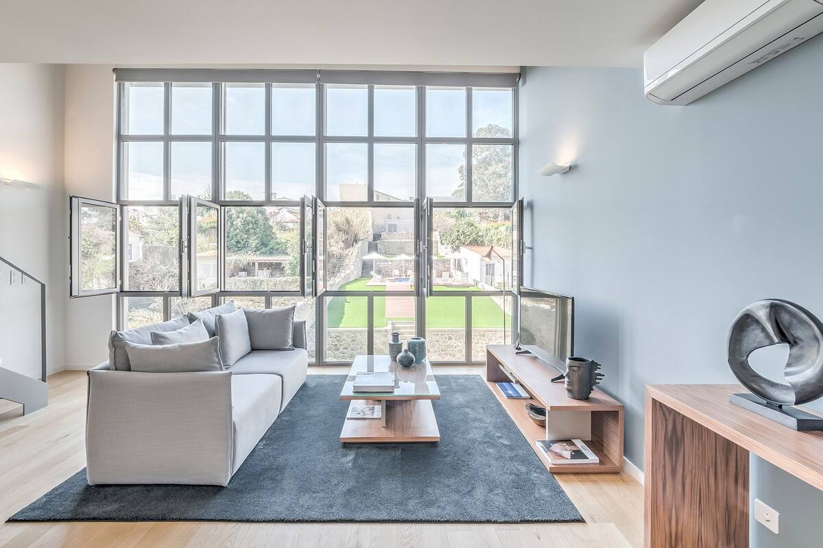 A modern living room with a large window, a sofa, a coffee table, and a TV stand.