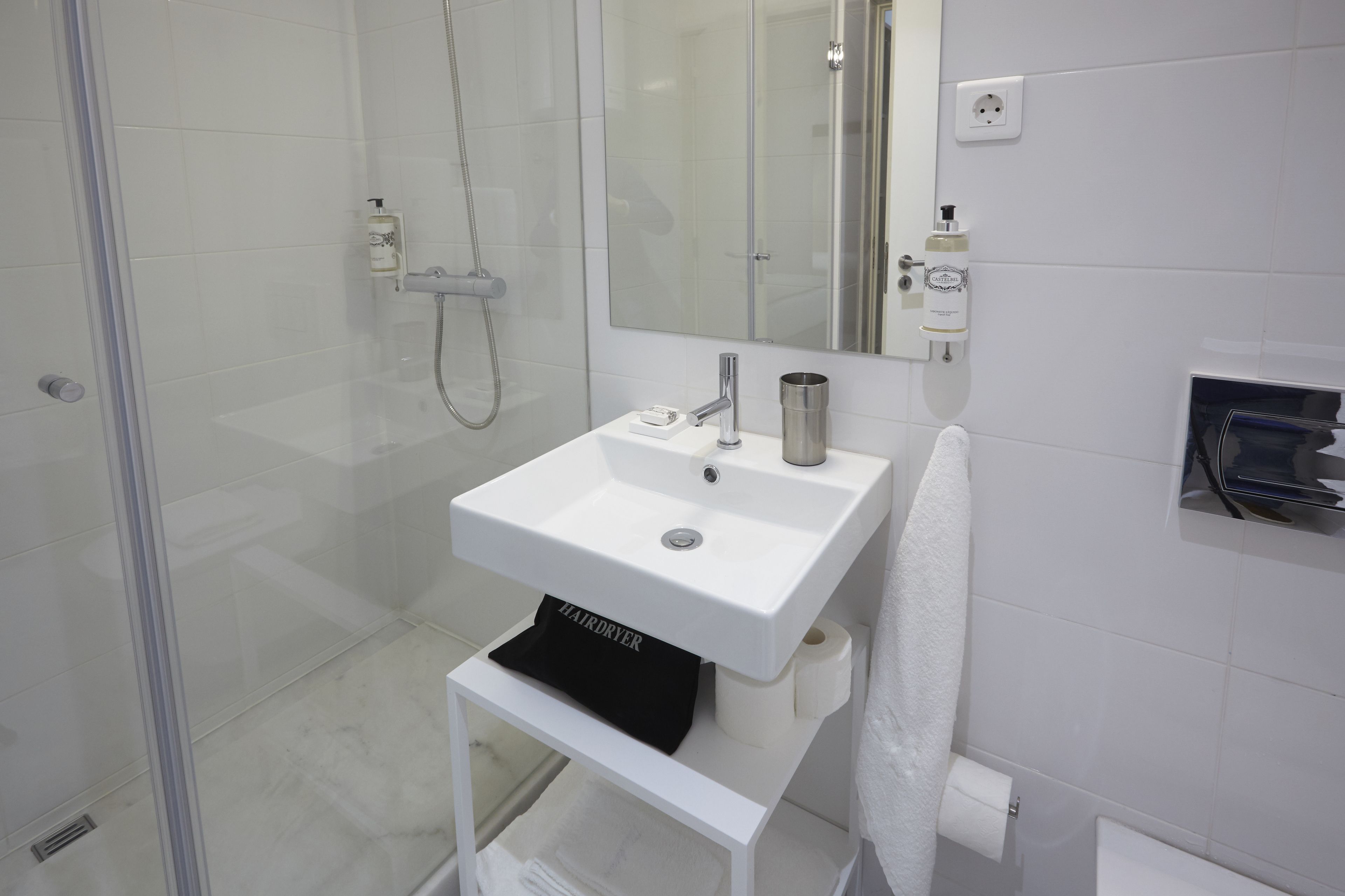Une salle de bain moderne avec un lavabo blanc, un miroir et une douche à parois de verre.