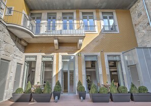 Un edificio de varios pisos con balcones, ventanas amplias y plantas en macetas.