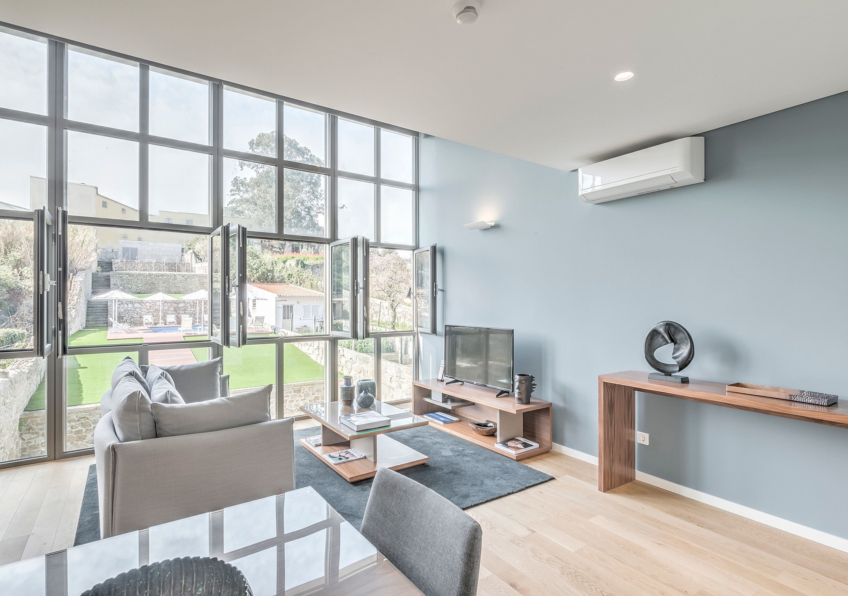Un salón amplio con ventanas grandes, un televisor de pantalla plana y un diseño minimalista.