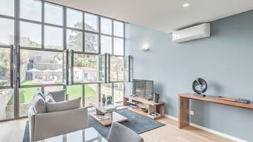 Un salón amplio con ventanas grandes, un televisor de pantalla plana y un diseño minimalista.