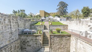 A stone staircase leading to a rooftop terrace with outdoor seating and a view of surrounding buildings.