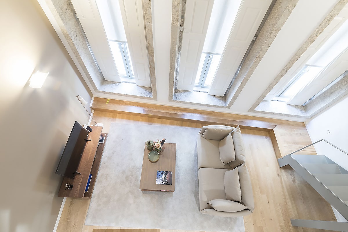 A high-ceilinged living room with a sofa, coffee table, and a TV.