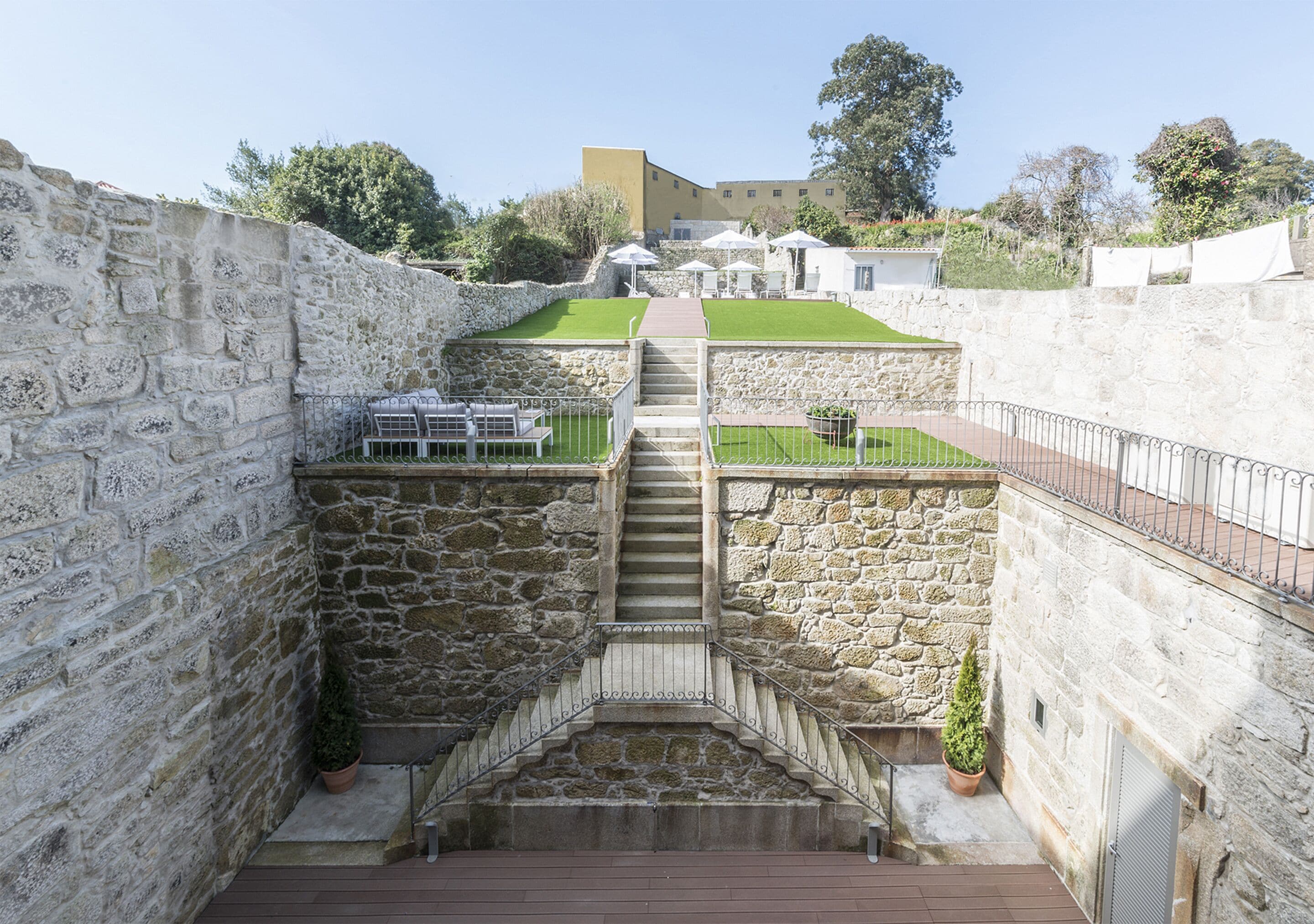 Una escalera de piedra que lleva a una terraza en la azotea con mobiliario exterior y vistas del paisaje circundante.