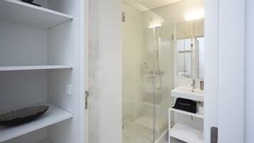 A modern bathroom with a glass-enclosed shower, white tiled walls, and a minimalist design.