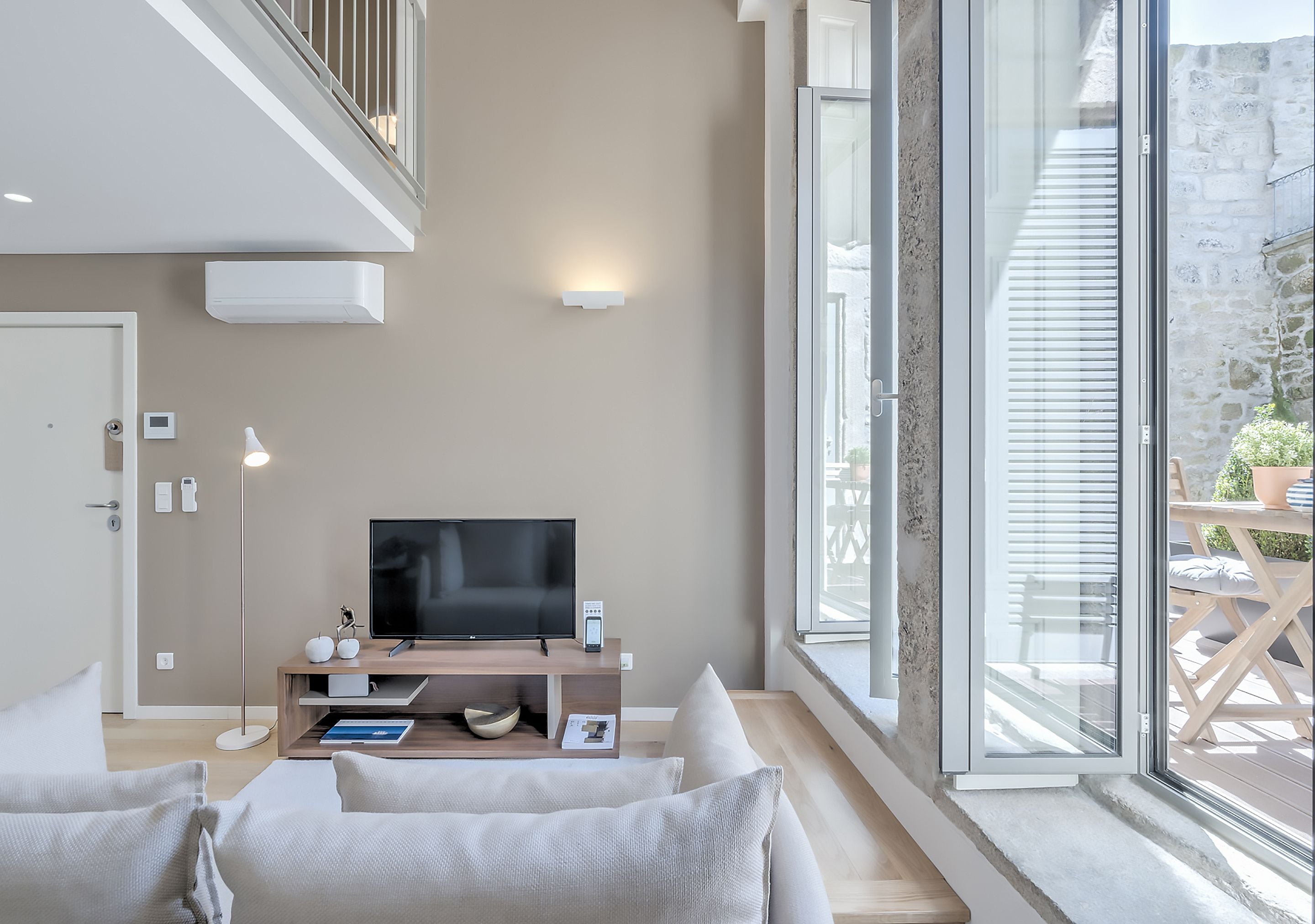 Una sala moderna con televisor de pantalla plana, un mueble de entretenimiento de madera y un amplio ventanal con vistas al exterior.