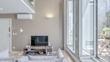 Una sala moderna con televisor de pantalla plana, un mueble de entretenimiento de madera y un amplio ventanal con vistas al exterior.