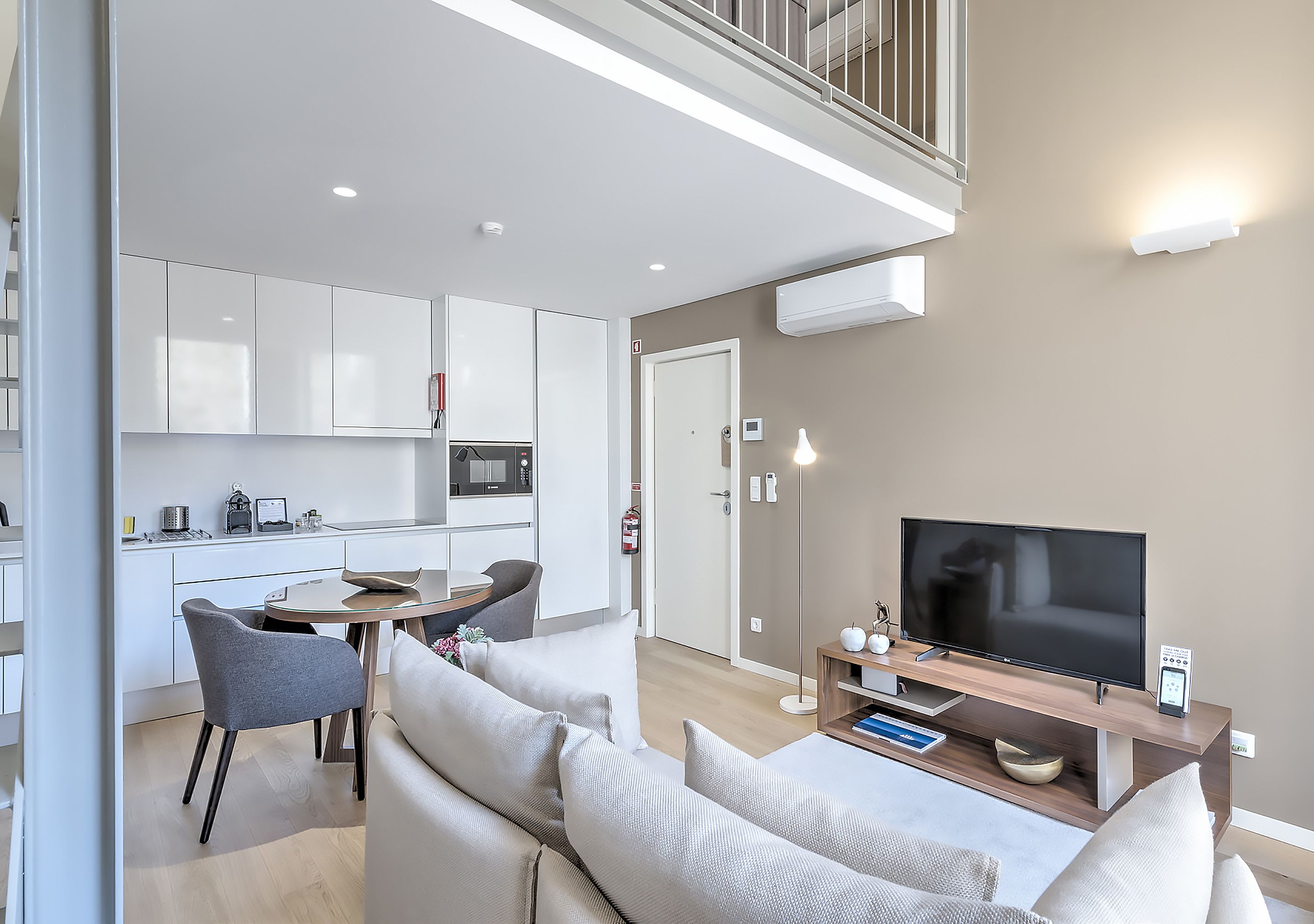 Un appartement moderne doté d’un coin repas, d’un salon avec télévision à écran plat et d’un balcon.