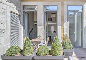 Un edificio moderno con un patio que tiene una mesa y sillas, rodeado de plantas en macetas.
