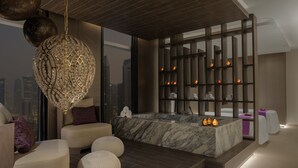 Una moderna spa con una vasca da bagno in marmo, un grande lampadario decorativo e vista sulla città.