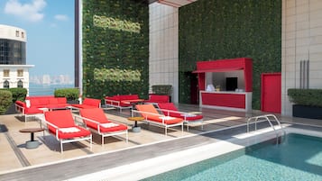 Una piscina al aire libre, sombrillas, sillones reclinables de piscina