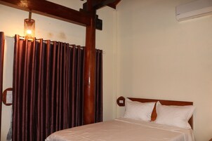 Habitación de hotel con estructura de cama de madera, cubrecama blanco y cortina con lámpara.