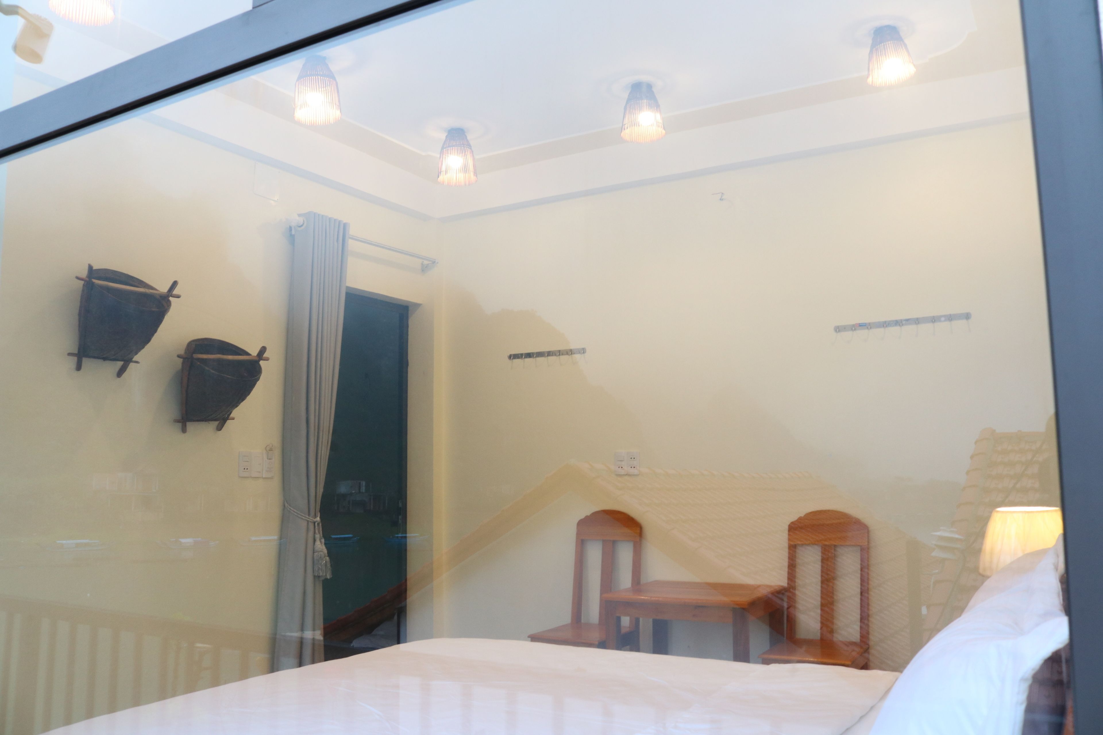 A hotel room with a bed, two chairs, a window, and a ceiling light fixture.