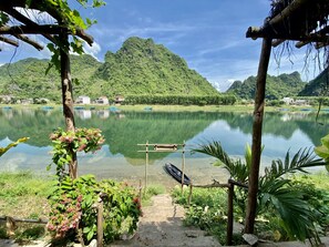A tranquil lake with a wooden dock, surrounded by lush greenery and mountains. - Phong Nha Coco Riverside Homestay (Bo Trach)