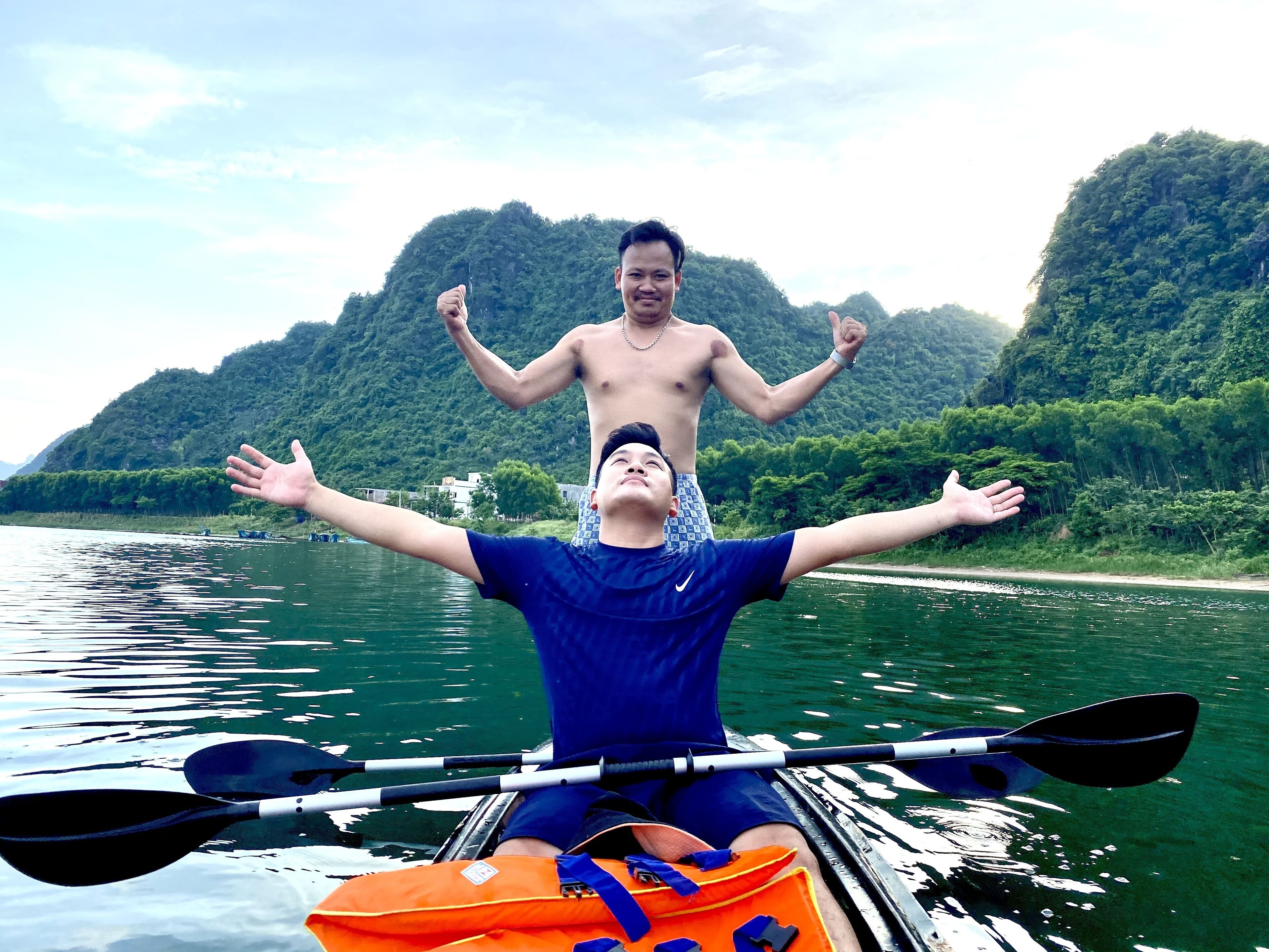 Eine Person paddelt mit einem Kajak auf einem Fluss vor einer gebirgigen Landschaft.