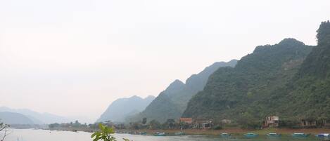 Un río con barcos y montañas al fondo.