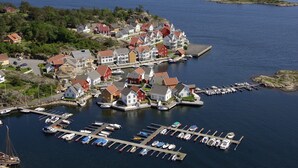 Een kustplaatsje met een jachthaven, huizen en een vuurtoren.