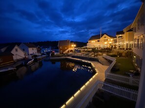 Een hotel aan het water met een aanlegsteiger, een zwembad en een goed verlicht buitengebied.