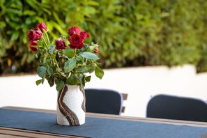 Un jarrón blanco con diseño negro y dorado que contiene rosas rojas sobre una mesa.
