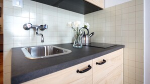 Une cuisine dotée d’un évier en acier inoxydable, de meubles de rangement en bois et d’un plan de travail noir.