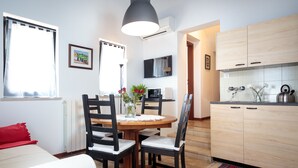 Un espace de vie compact comprenant un coin repas, une cuisine et un petit coin salon.