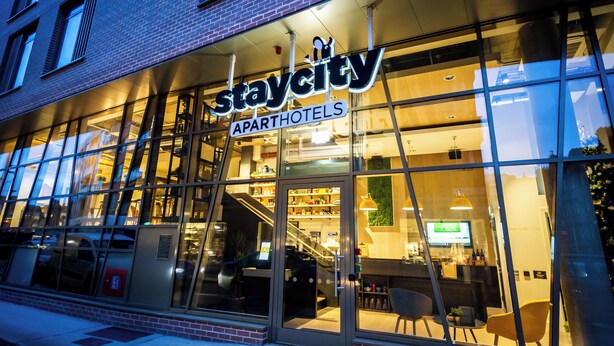 Un hotel-apartamento Staycity con amplios ventanales, una escalera a la vista y una zona de recepción.