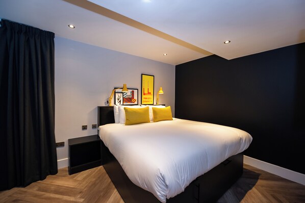 Quarto moderno com cama grande, paredes escuras e decoração minimalista.