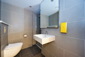 Une salle de bain moderne équipée de toilettes, d’un lavabo et d’une douche.